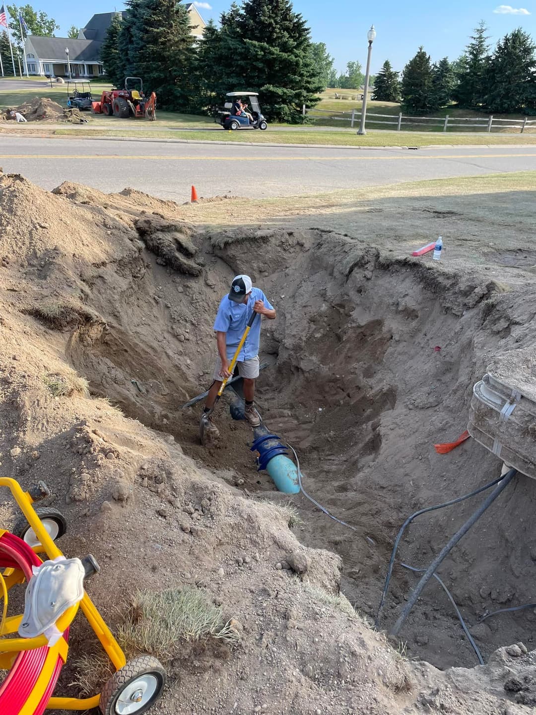 Construction worker digging a trench for plumbing installation in a residential area.